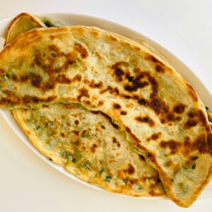 Close-up of delicious homemade stuffed flatbread on a white tray, perfect for breakfast or a savory meal.