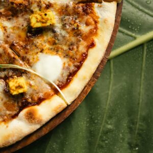 Close-up of a mouthwatering paneer pizza on a natural leaf background, shot in Surat.