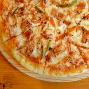 Delicious close-up view of a hot chicken pizza topped with onions and peppers.