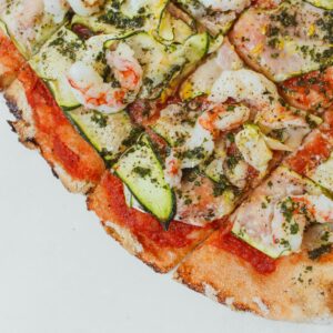 A delectable Italian seafood pizza topped with shrimp and zucchini slices, perfect for gourmet dining.