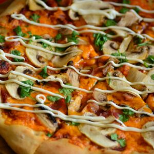 Delicious mushroom pizza with creamy toppings and fresh herbs in close-up.